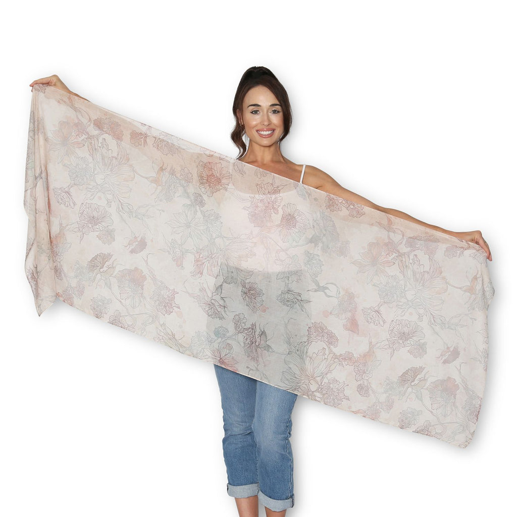 Woman holding up The Artist Label Nature's tapestry floral scarf, in vintage orange and apricot colours