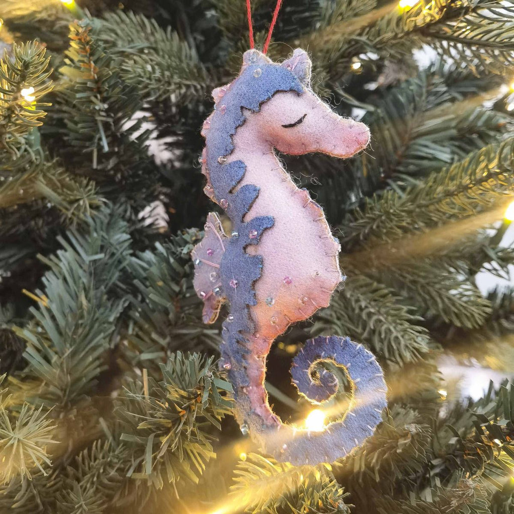 Decorative felt seahorse ornament on a Christmas tree with lights.