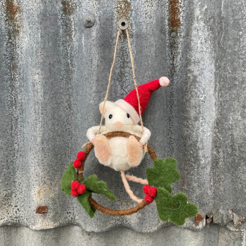 Felted mouse ornament with a red Santa hat hanging on a rustic metal surface.