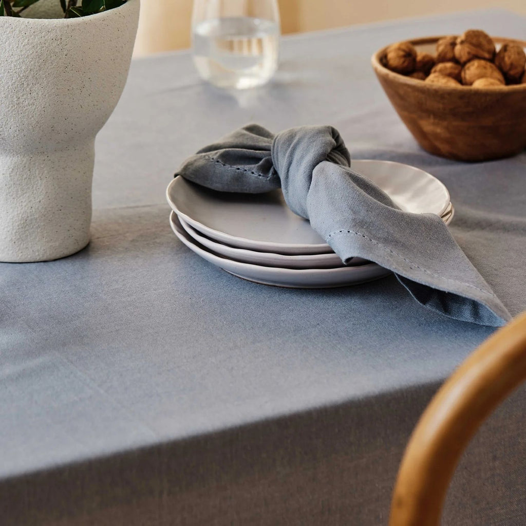 Table setting with plates, mineral blue napkin, and bowl on a mineral blue tablecloth.