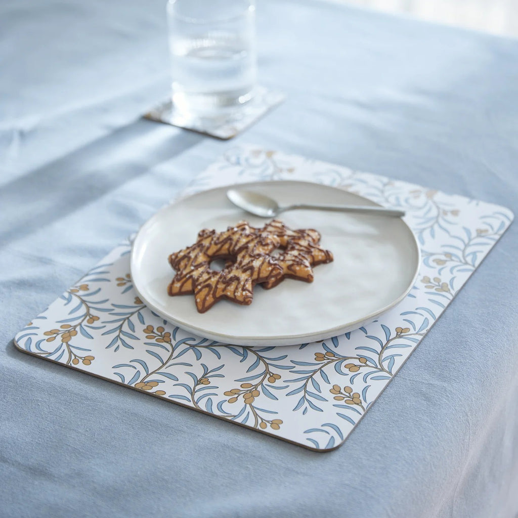 Placemat with a plate of cookies and a glass on a mineral blue tablecloth