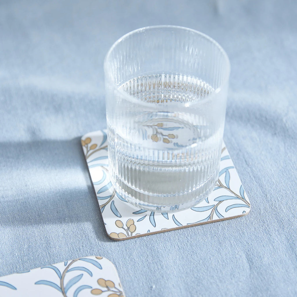 Clear glass of water on a decorative coaster with a mineral blue tablecloth