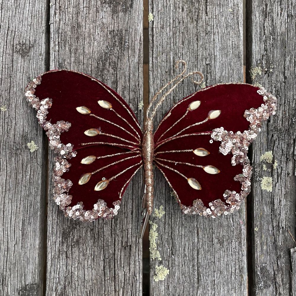 Decorative butterfly with maroon wings and gold accents on a wooden background
