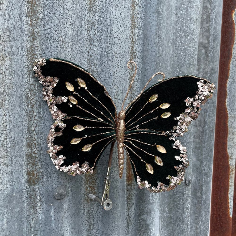 Decorative butterfly with dark green and gold details on a textured metal surface.