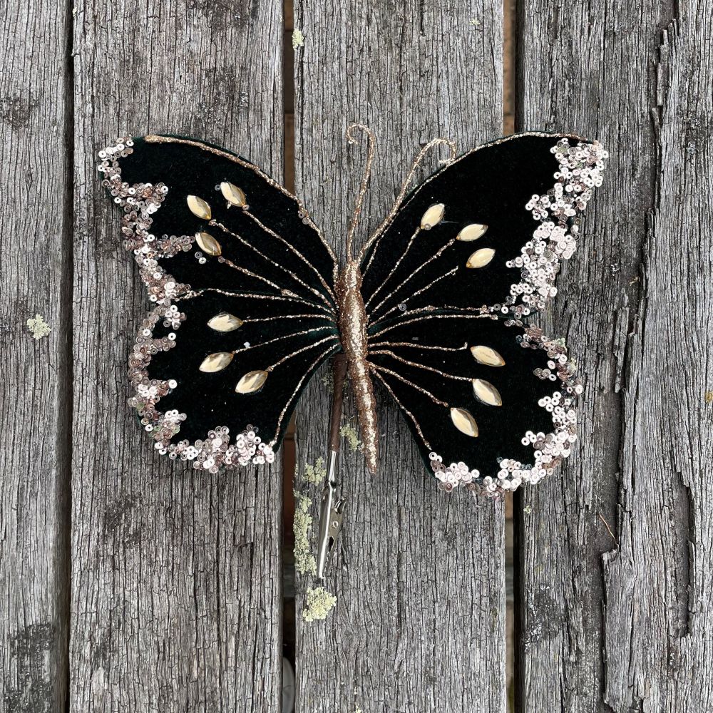 Decorative butterfly with dark green, gold, and white on a wooden background