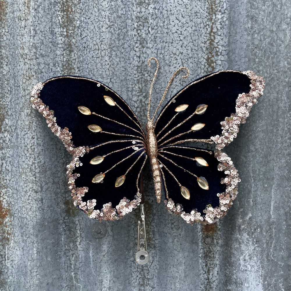 Velvet butterfly in navy blue with gold embellishments on a corrugated steel background