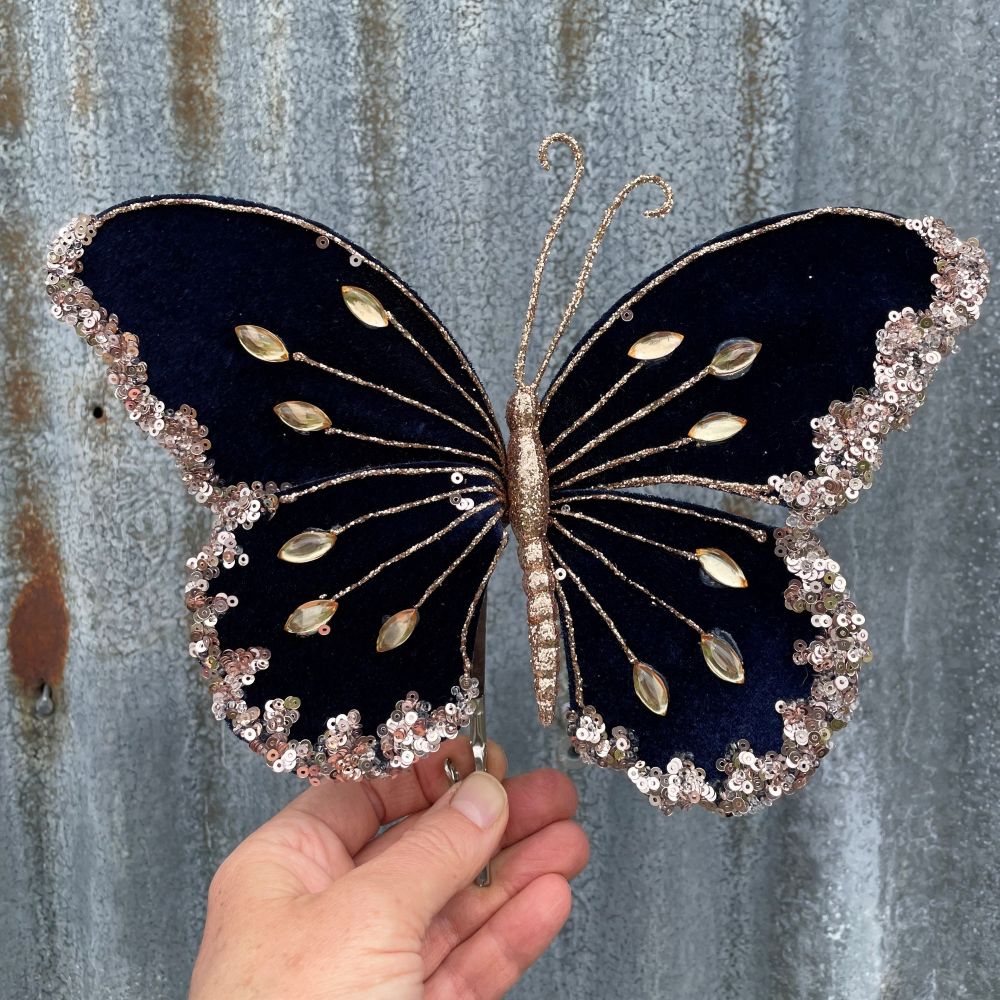 Velvet butterfly in navy blue with gold embellishments on a corrugated steel background