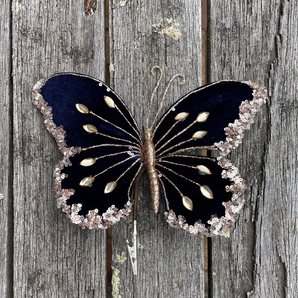 Velvet butterfly in navy blue with gold embellishments on a wood table
