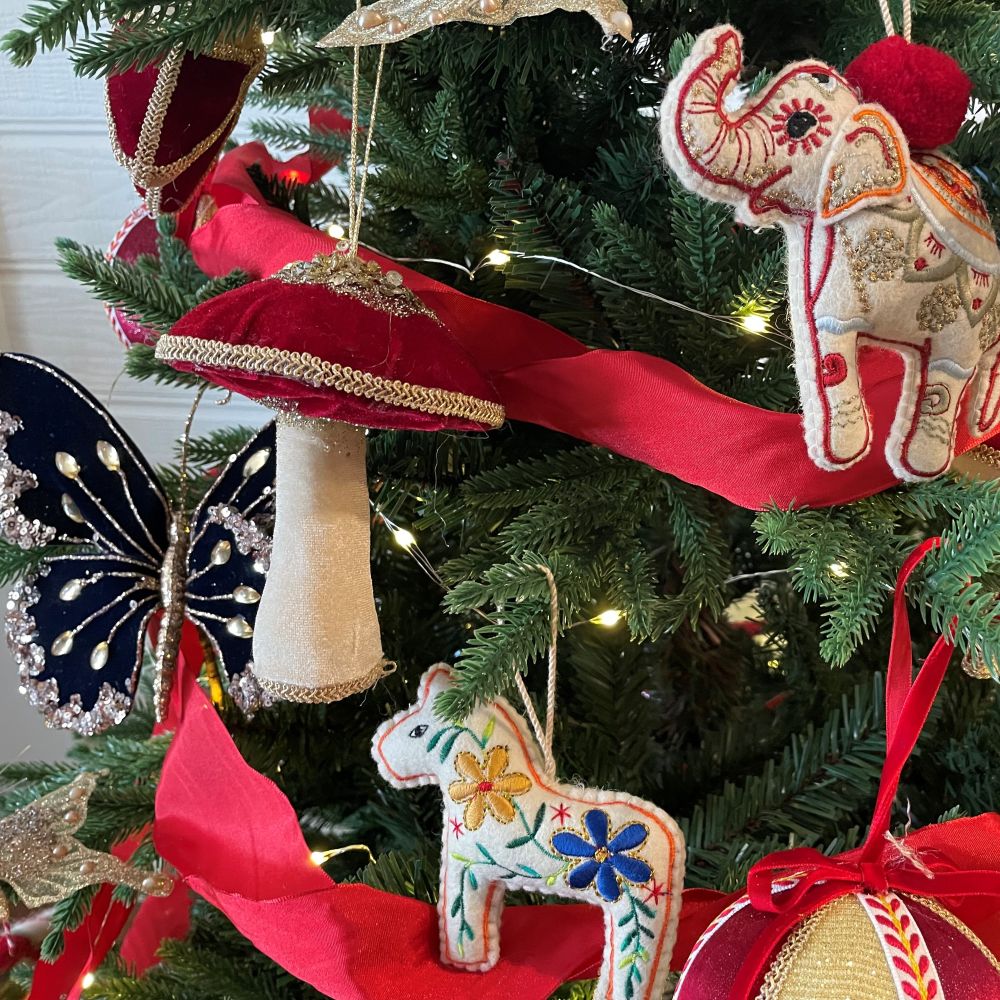 Decorative Christmas tree with colorful ornaments including a butterfly, elephant, and floral-patterned horse.