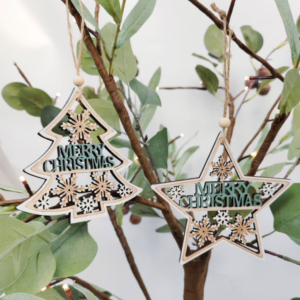Wooden 'Merry Christmas' tree and star ornaments hanging on a branch with green leaves.