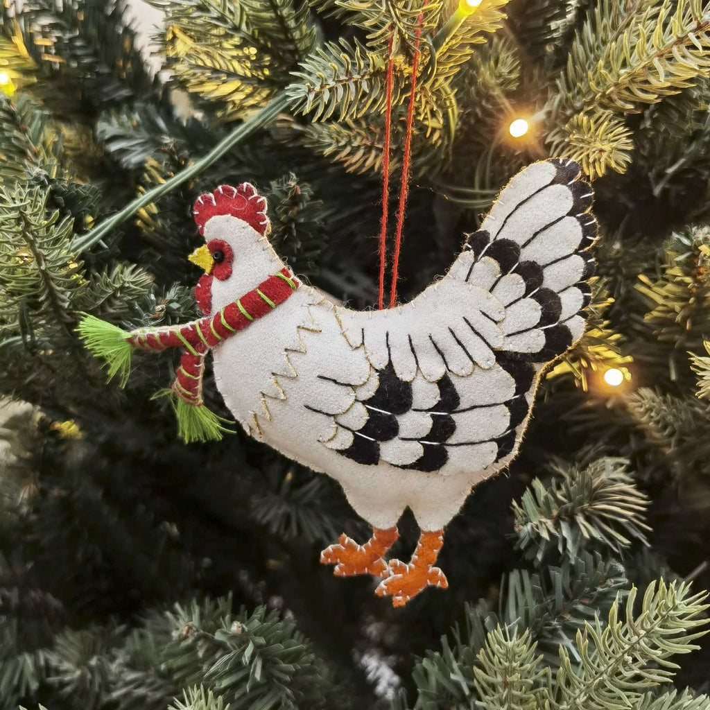 Decorative rooster ornament hanging on a Christmas tree.