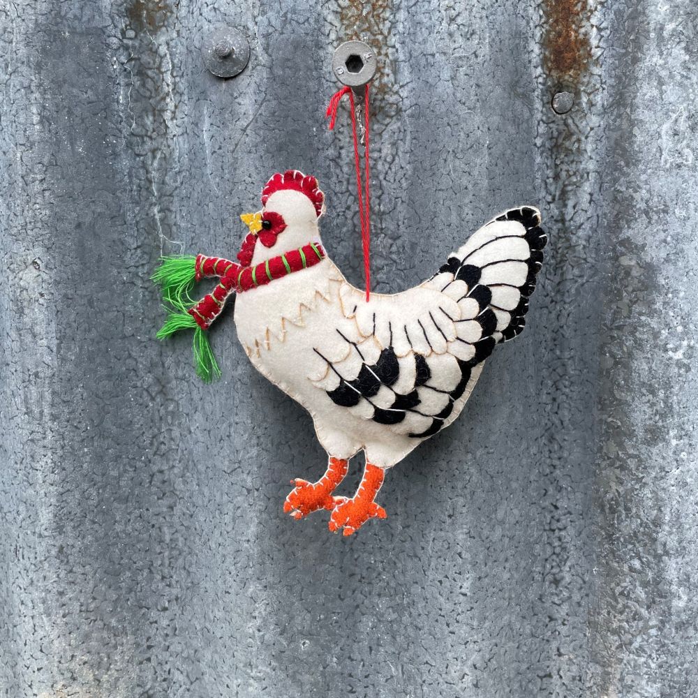 Decorative Felt rooster ornament with a red scarf on a textured metal surface