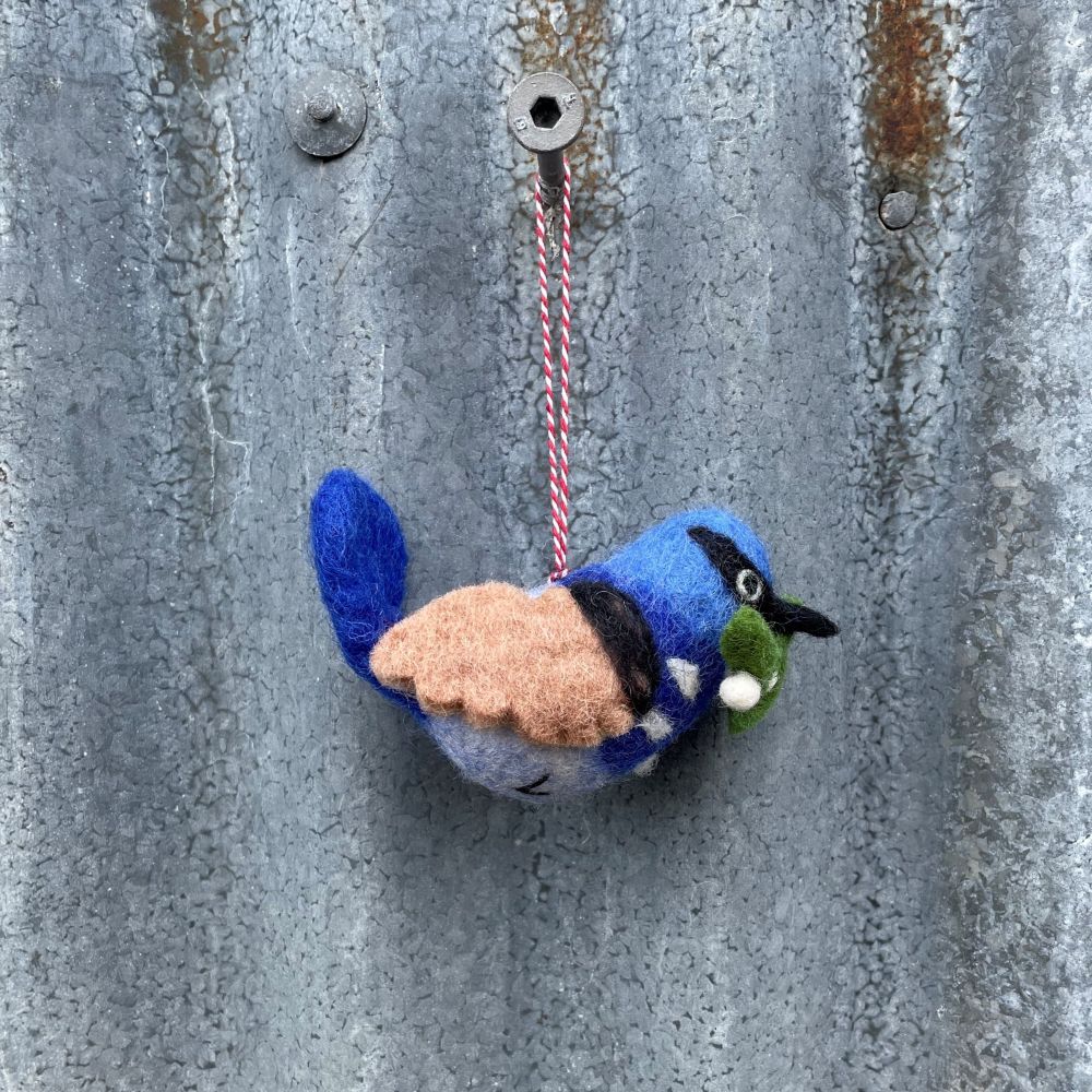 Felted Australian blue wren bird ornament hanging on a textured metal surface