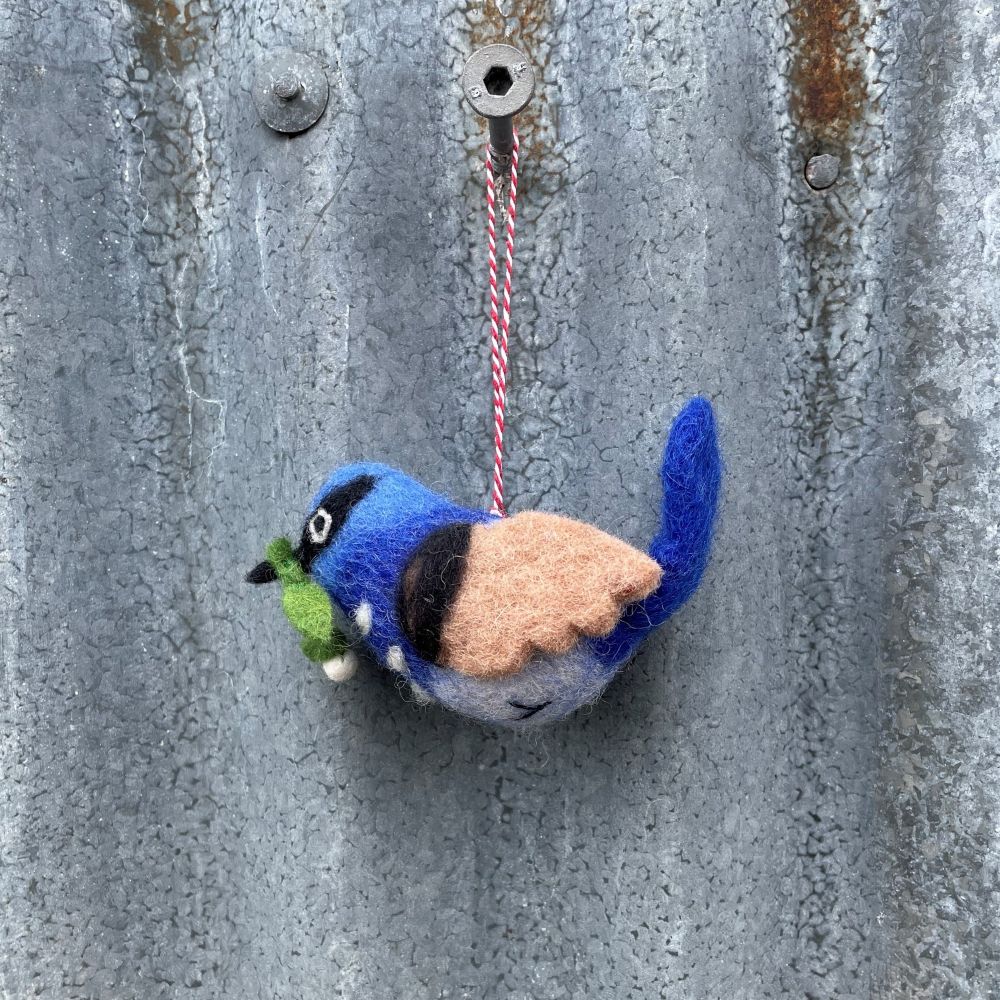 Felted Australian blue wren bird ornament hanging on a textured metal surface