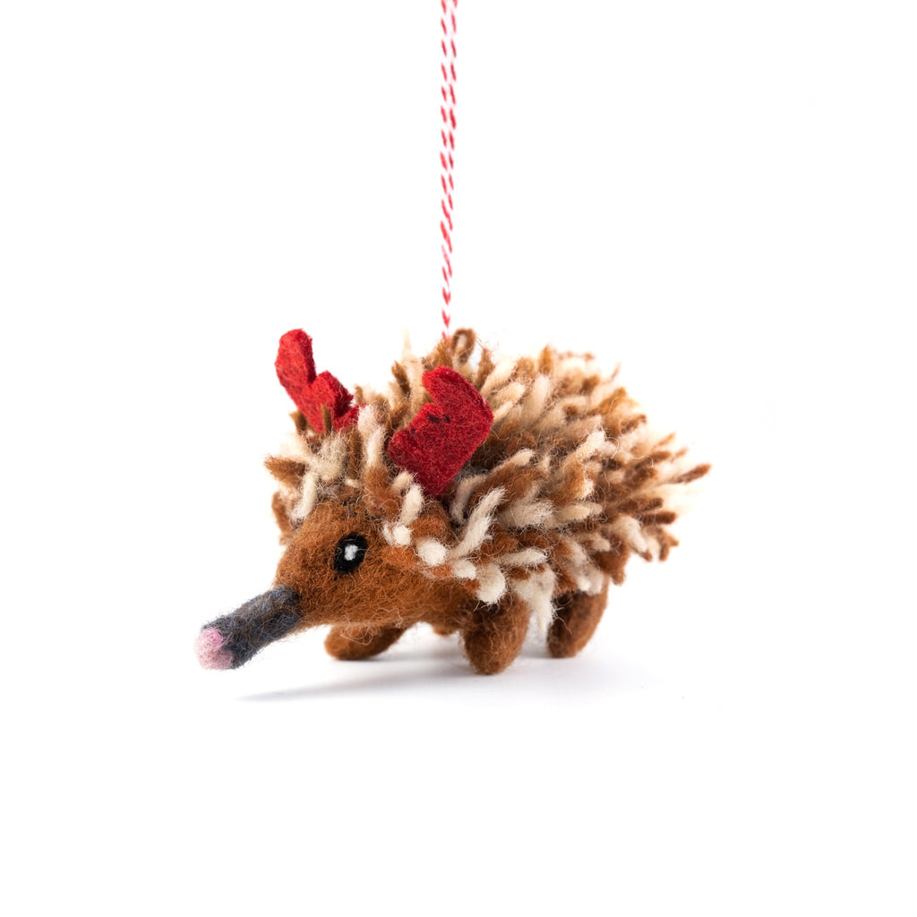 Felted echidna ornament with red antlers on a white background