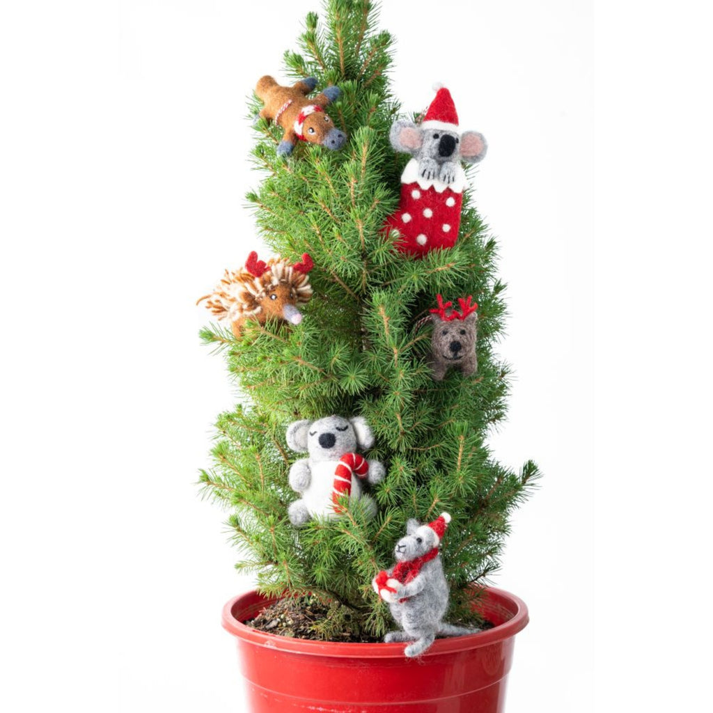 Small potted Christmas tree with decorative animal ornaments on a white background