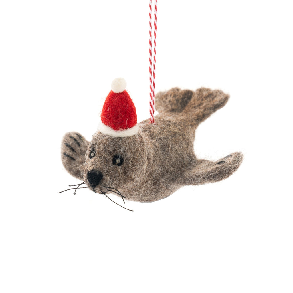Felt seal ornament wearing a Santa hat on a white background