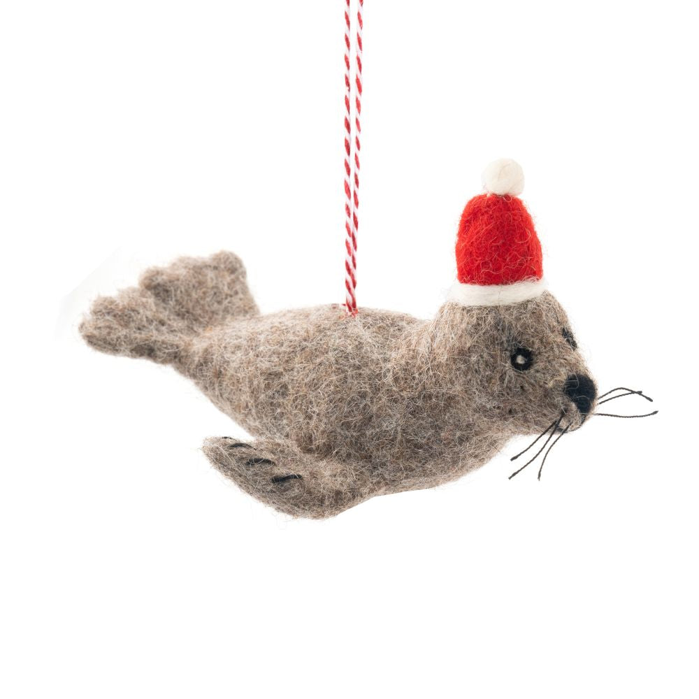 Felted fur seal ornament with a red Santa hat on a white background