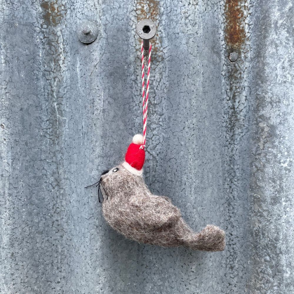 Felted fur seal resembling with a red and white string on a textured metal surface