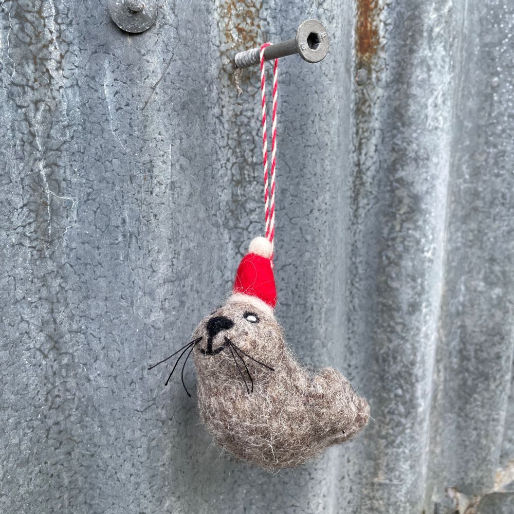 Felted fur seal resembling with a red and white string on a textured metal surface