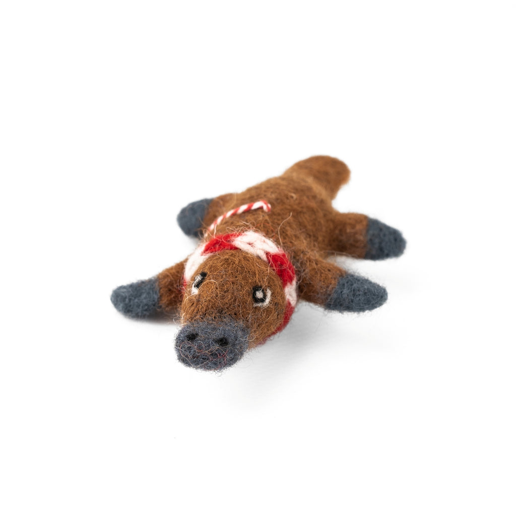 Felted platypus ornament with a red scarf hanging on a white background