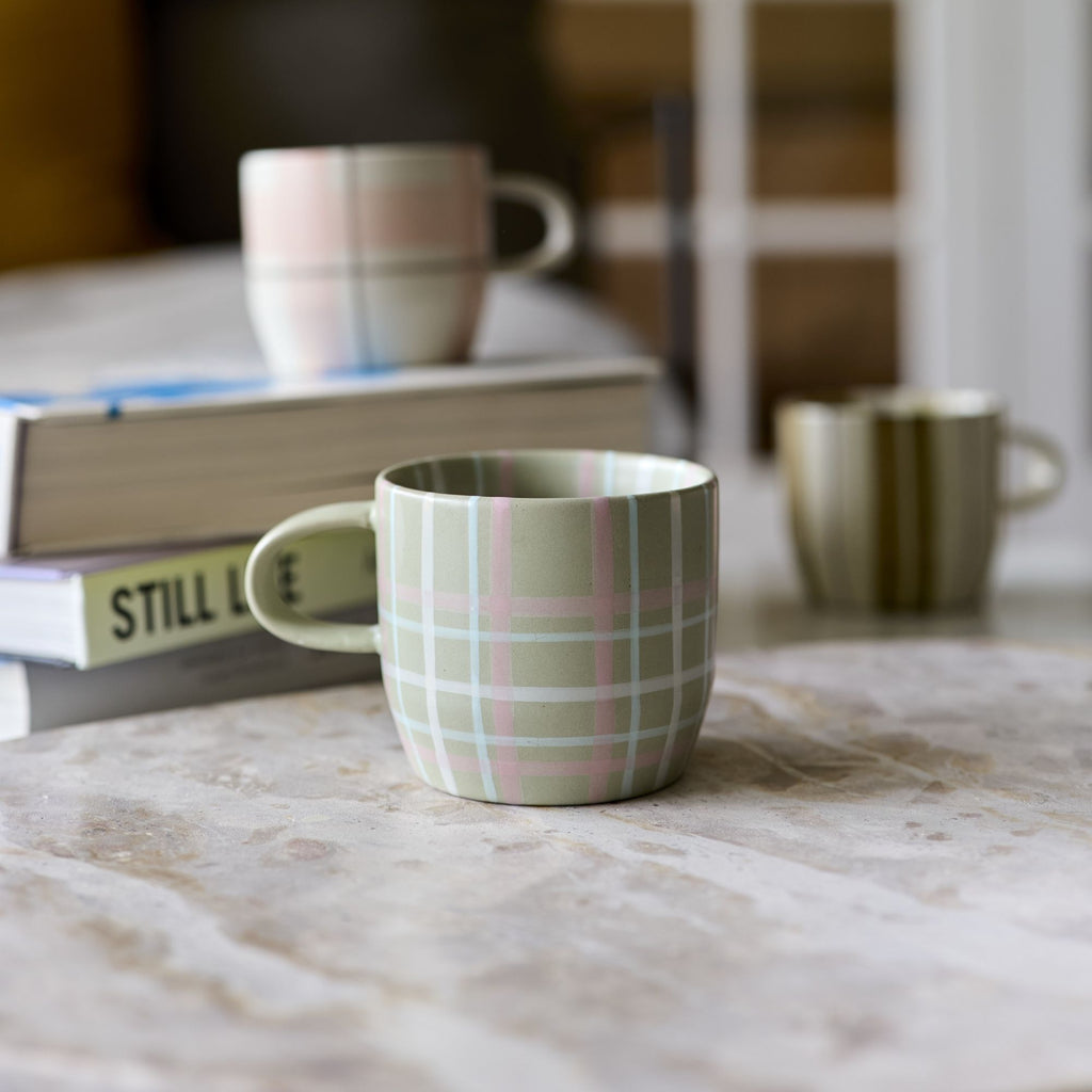 Twig and Feather - The Cat's Pyjamas mug in sage and blush check - by Robert Gordon - shown near books on coffee table