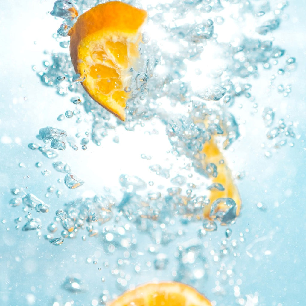 Orange slices splashing in water with bubbles
