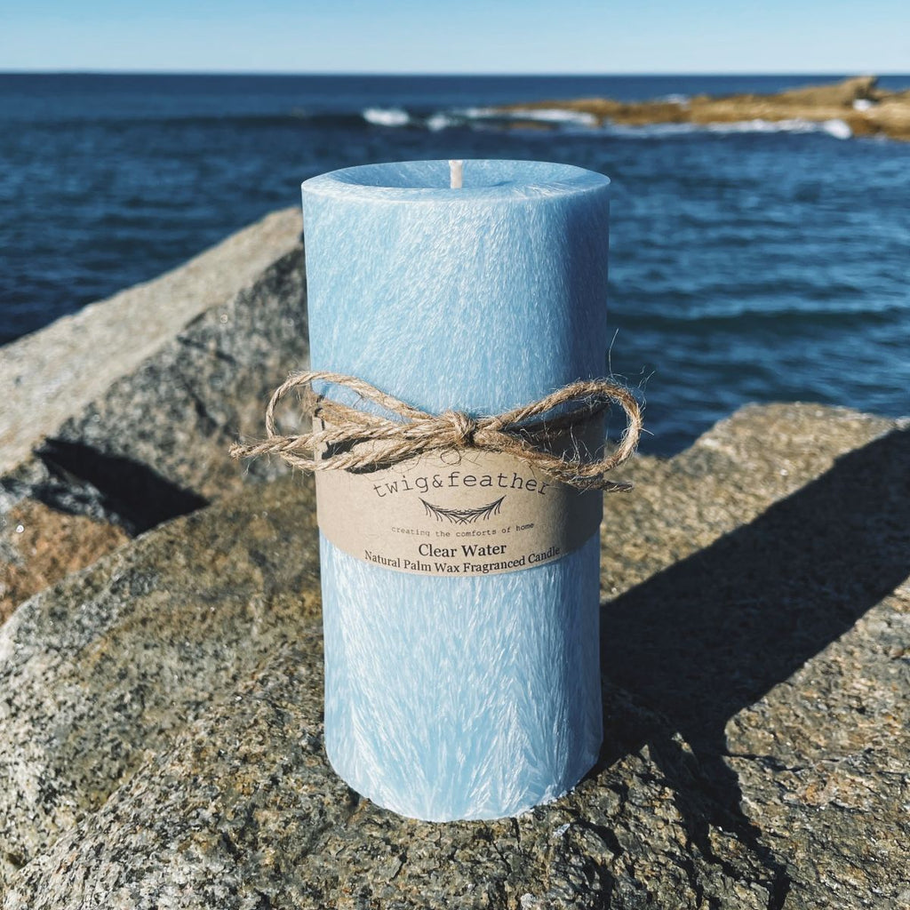Twig and Feather clear water scented Blue palm wax pillar candle on a rock near ocean in Bermagui
