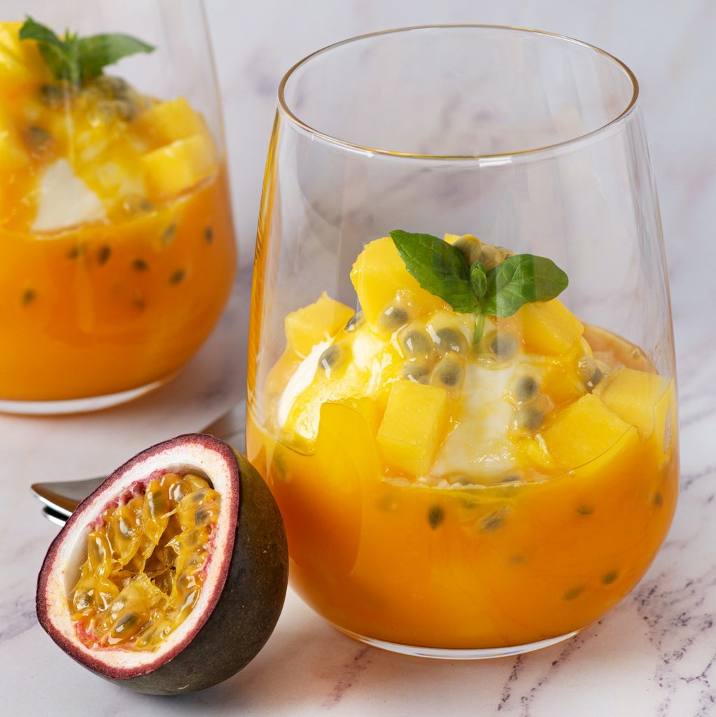 Two glasses of papaya fruit salad with passion fruit on a marble surface